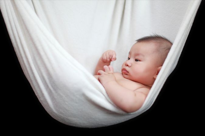 depositphotos 16173371 naked baby sleeping in white hammock sling isolated on a black background